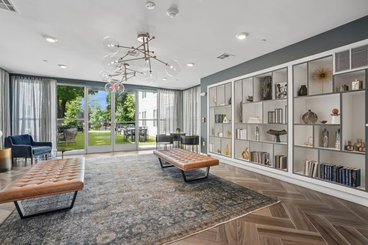 Lounge with modern shelves, glass doors, and leather benches on patterned rugs.