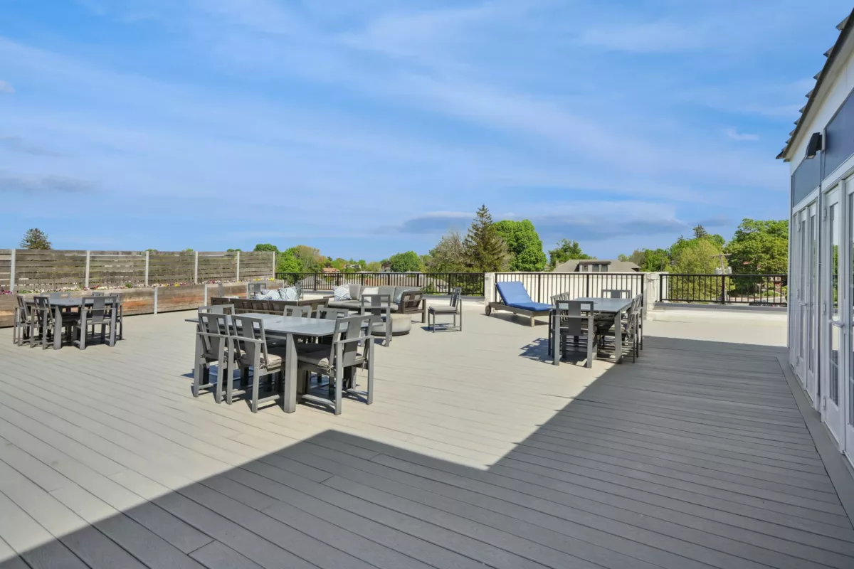 Spacious rooftop with tables, lounge chairs, and skyline views beyond the railing.