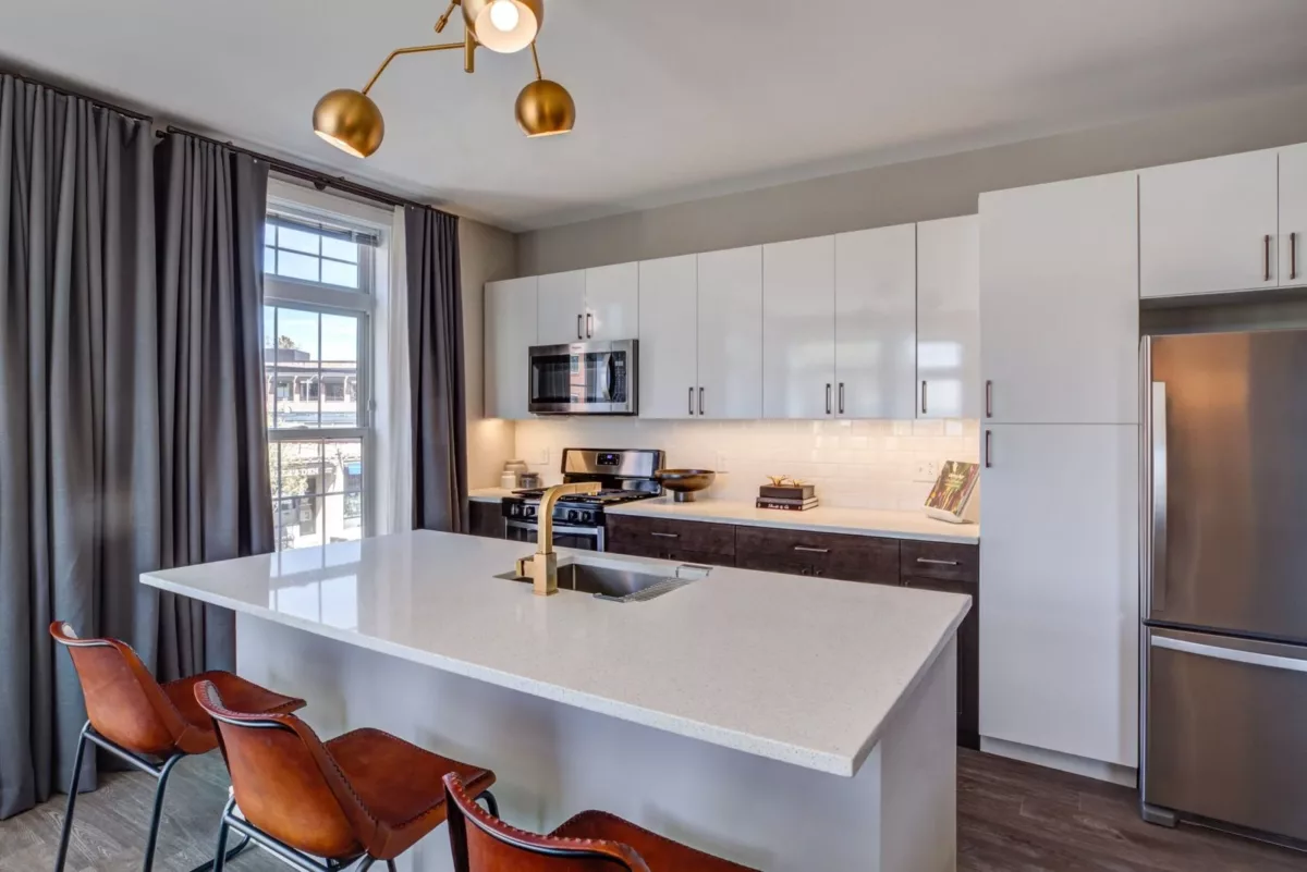 The Bradford apartment kitchen with two-tone cabinets, stainless steel appliances, quartz countertops, and large island with seating