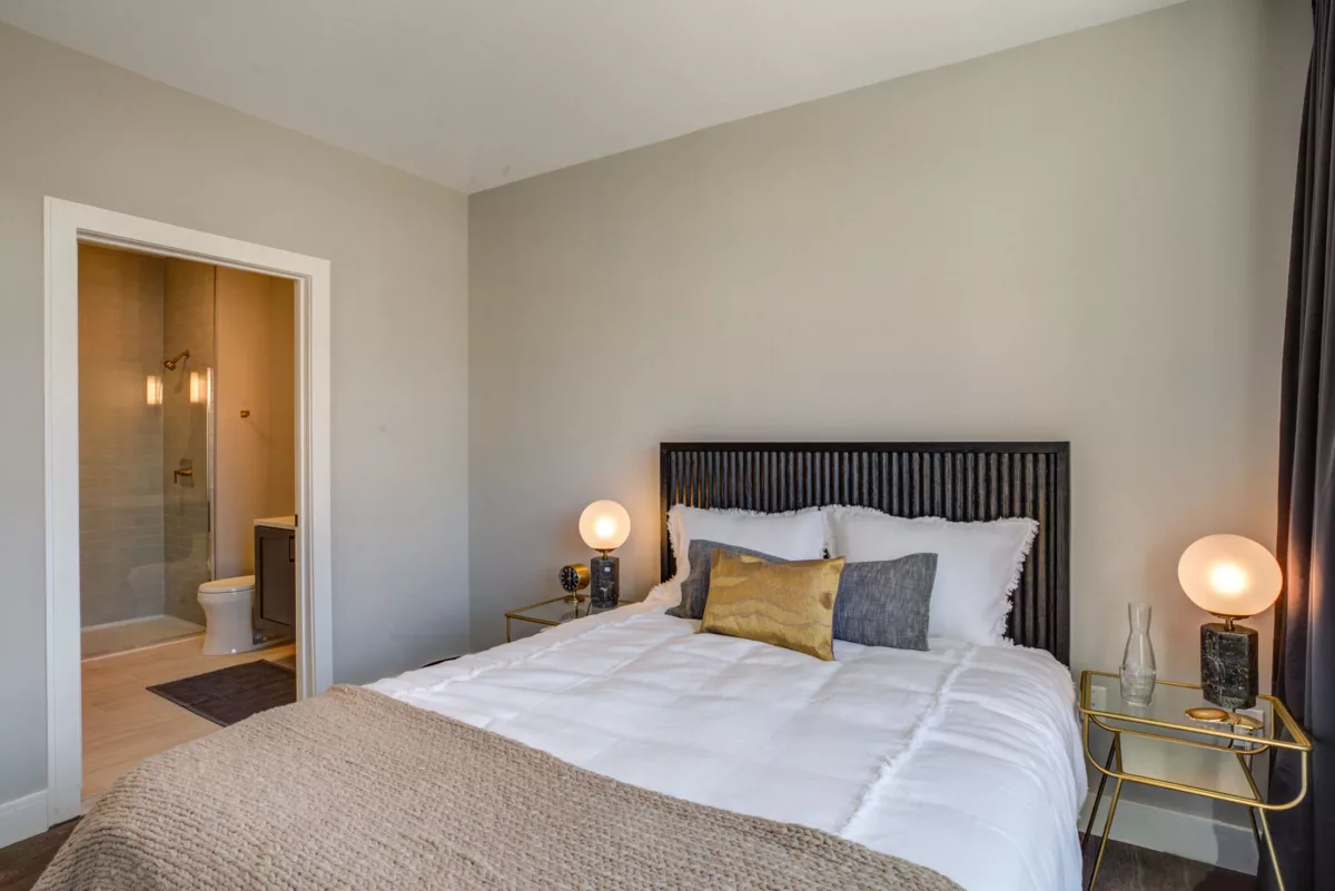 Apartment master bedroom with bed, nightstands, and private bathroom at The Bradford