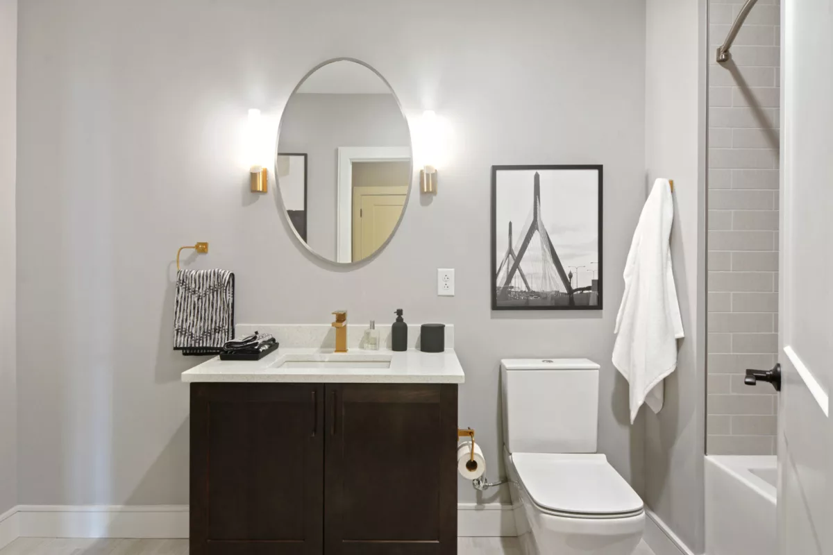 Restroom at The Bradford, featuring white quartz countertops, dark cabinets, round mirror